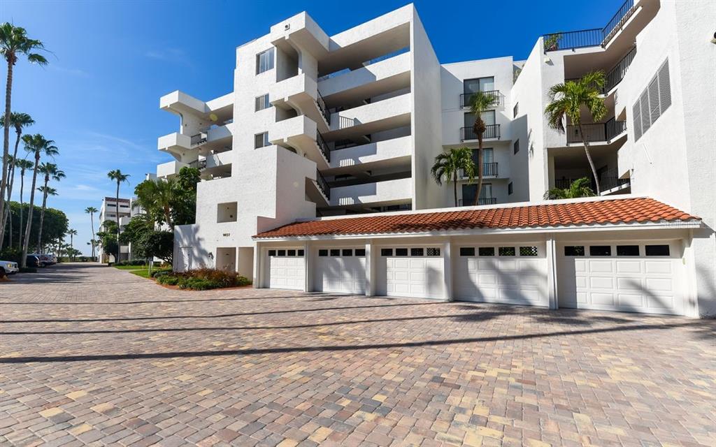 A multi-story white apartment building features a row of garages with a tiled roof — 1485 GULF OF MEXICO DRIVE UNIT 109, LONGBOAT KEY, FL