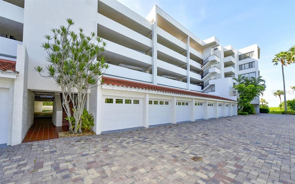 A row of white garage doors sits beneath a tiled roof in front of a building — 1485 GULF OF MEXICO DRIVE UNIT 109, LONGBOAT KEY, FL