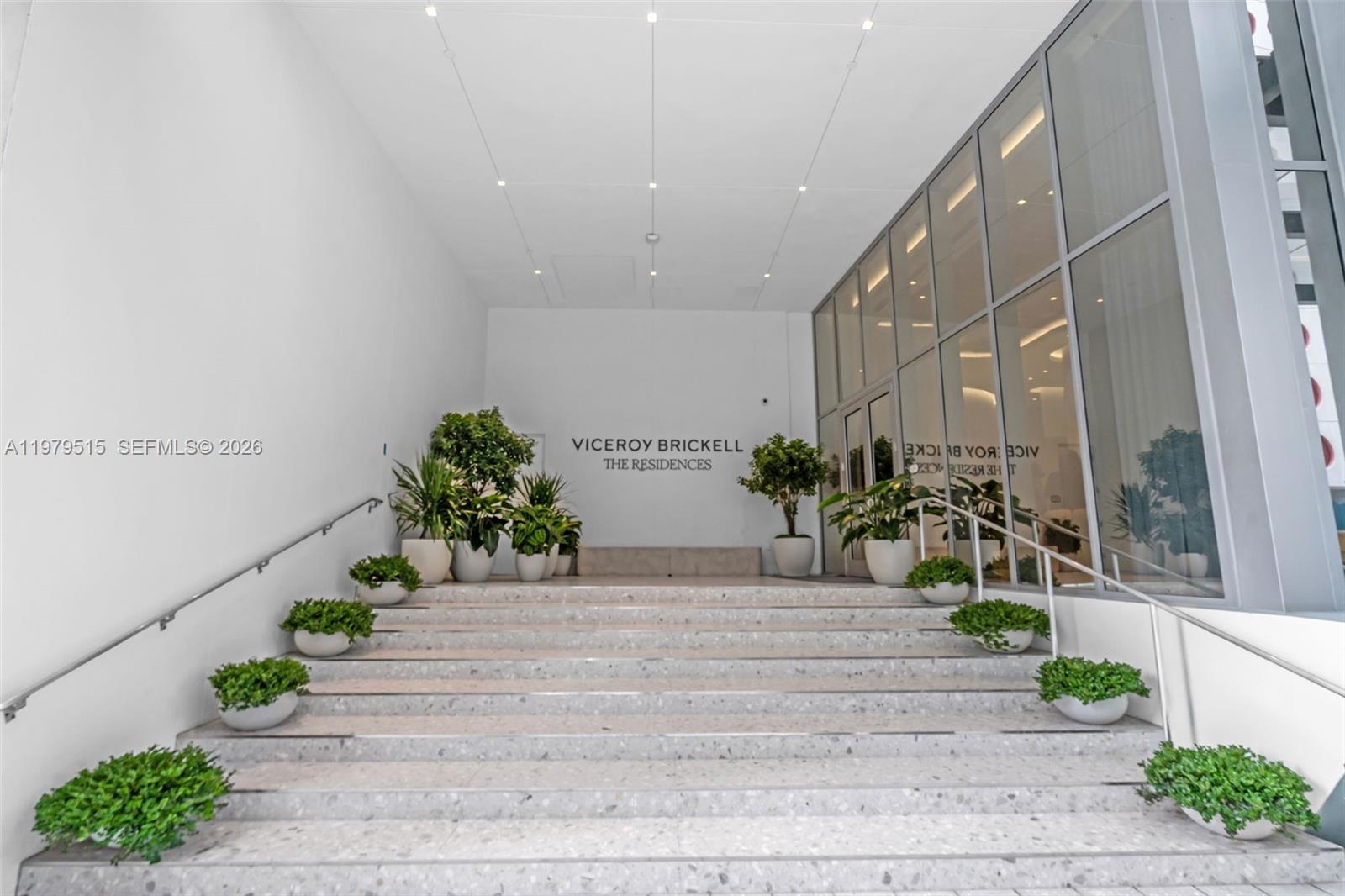 A wide stone staircase with potted plants leads to the entrance of a modern building — 77 SE 5TH ST # 2405, Miami FL 33131, MIAMI, FL