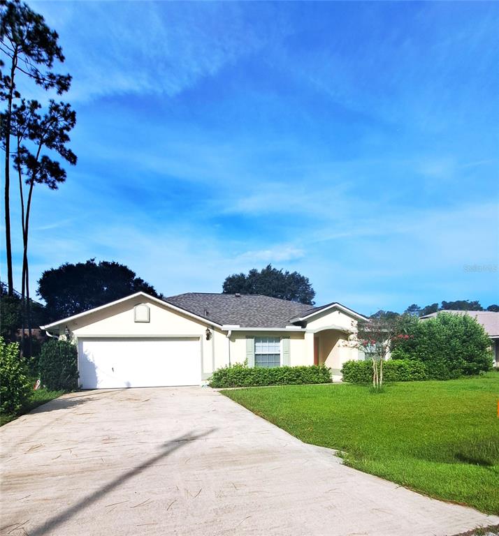 A single-story house with a white garage, beige siding, and a concrete driveway — 16 LLOSHIRE PATH, PALM COAST, FL