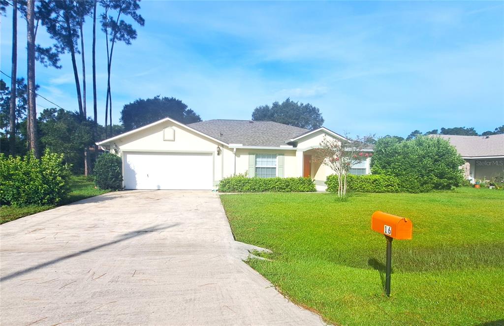 A single-story house with a white garage, light-colored siding, and a bright orange mailbox — 16 LLOSHIRE PATH, PALM COAST, FL