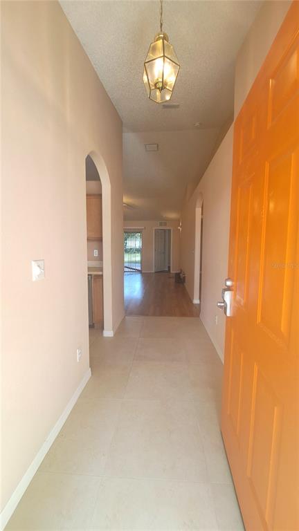 An interior view of a home entryway with light tile flooring and an orange door — 16 LLOSHIRE PATH, PALM COAST, FL