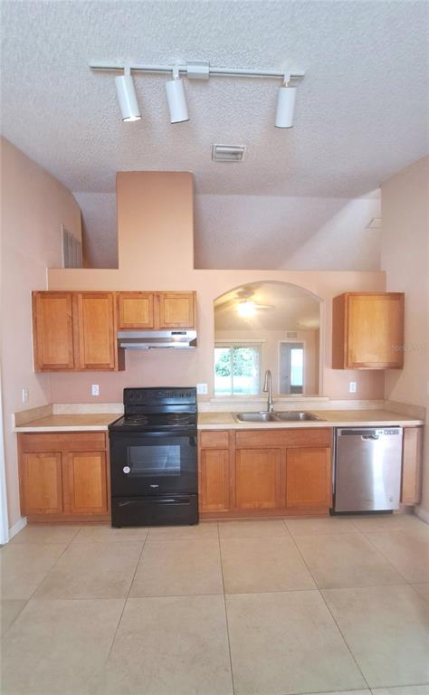 A kitchen features light wood cabinets, a black stove, a stainless dishwasher, and tile flooring — 16 LLOSHIRE PATH, PALM COAST, FL