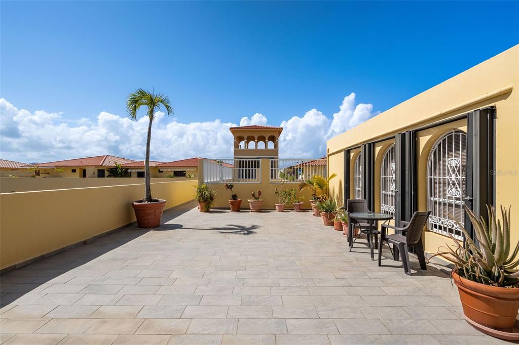 A spacious outdoor rooftop terrace features tiled flooring, potted plants, and a small seating area — 295 Palmas Inn Way PALMAS INN WAY UNIT 406, HUMACAO, PR