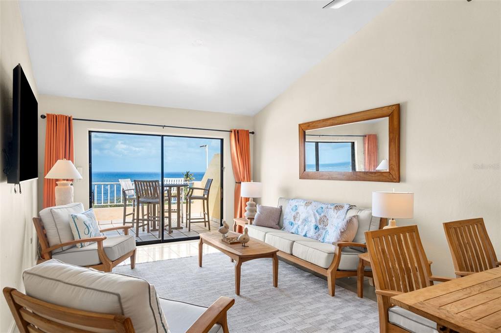 A living room features a sofa, armchairs, a coffee table, and a balcony overlooking the ocean — 295 Palmas Inn Way PALMAS INN WAY UNIT 406, HUMACAO, PR