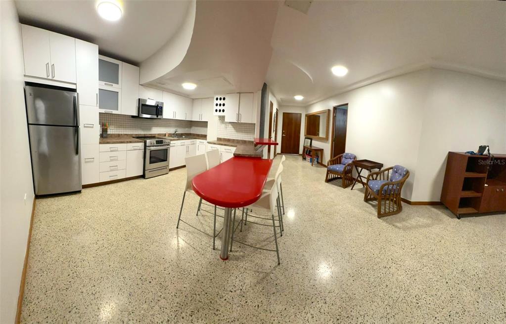 A kitchen with white cabinets and a red island sits in an open-concept living area — 185 CALLE PINE GROVE UNIT B-1, CAROLINA, PR