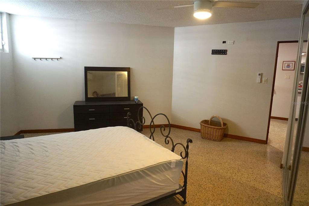 A bedroom features a metal bed frame, a dark dresser with a mirror, and terrazzo flooring — 185 CALLE PINE GROVE UNIT B-1, CAROLINA, PR