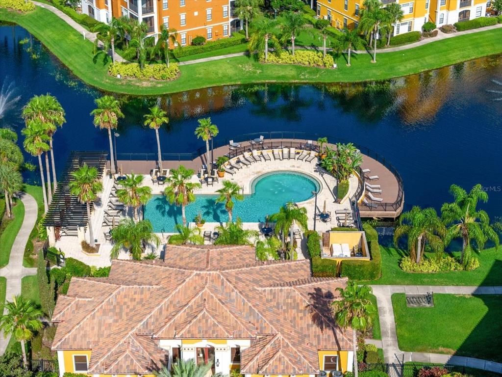 An aerial view shows a swimming pool and deck area situated beside a lake — 8377 38TH STREET CIRCLE E UNIT 106, SARASOTA, FL