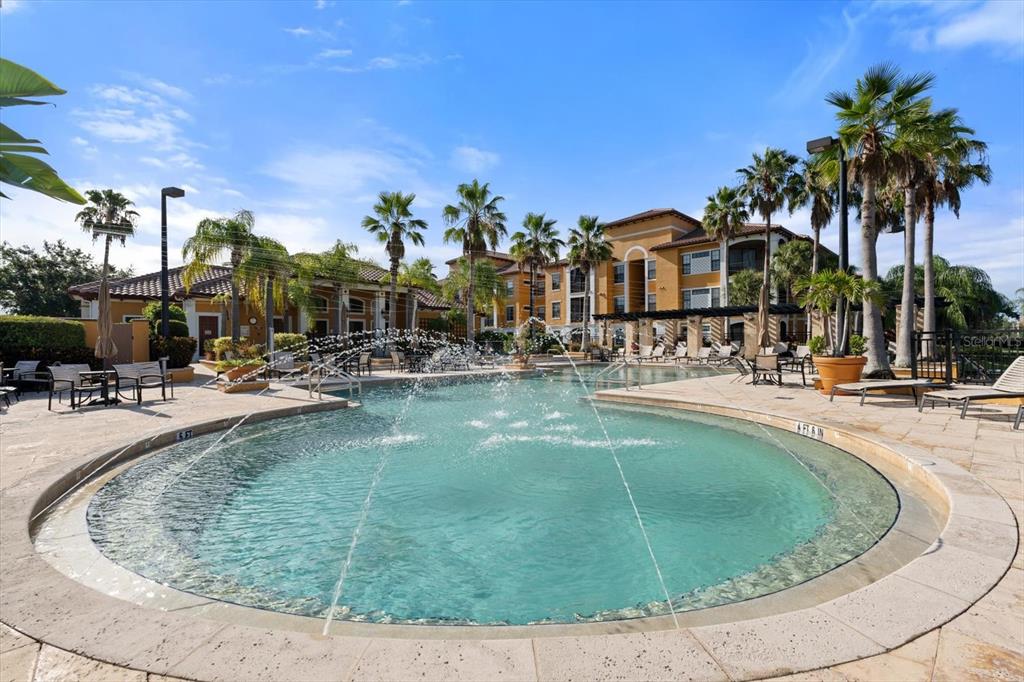 A swimming pool with fountains is surrounded by a stone deck and palm trees — 8377 38TH STREET CIRCLE E UNIT 106, SARASOTA, FL