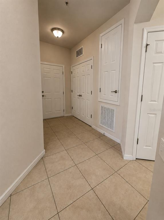 A tiled entryway features white doors, a ceiling light, and a wall-mounted HVAC vent — 3338 ROBERT TRENT JONES DR UNIT 203, ORLANDO, FL