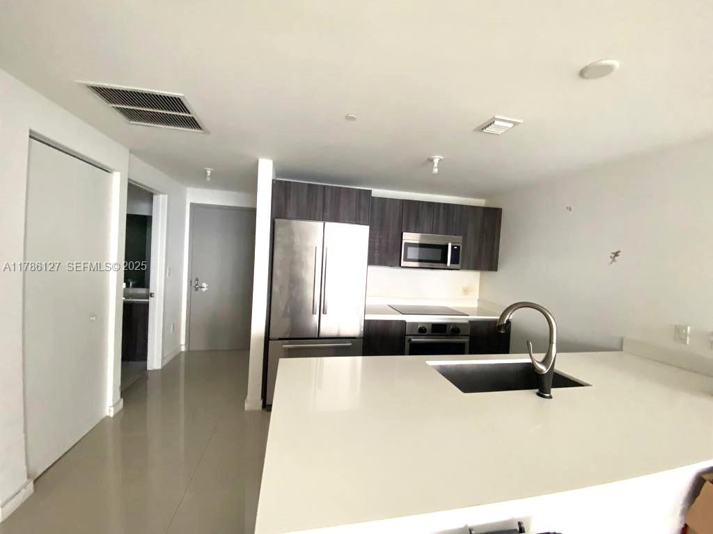 A kitchen features dark wood cabinets, stainless steel appliances, and a white quartz island countertop — 488 NE 18th St # 4905, Miami FL 33132, MIAMI, FL
