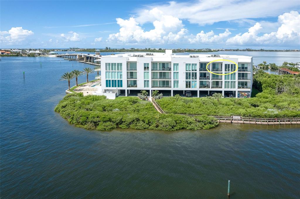 An aerial view of a modern white multi-story apartment building surrounded by water and mangroves — 1375 BEACH ROAD UNIT 309, ENGLEWOOD, FL