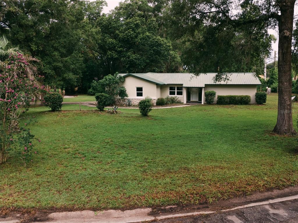 A single-story house with a metal roof sits on a large, grassy lot with trees — 14522 SE 1ST AVENUE RD, SUMMERFIELD, FL
