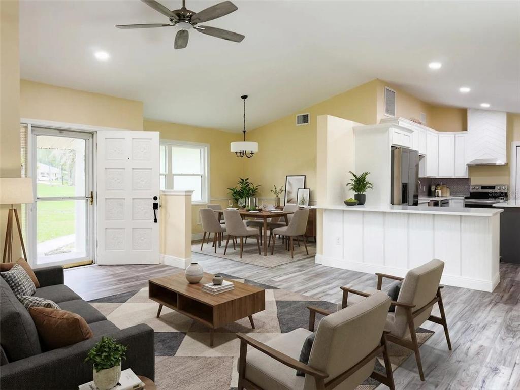 An open-concept living and dining area features light wood flooring, white cabinets, and neutral furniture — 14522 SE 1ST AVENUE RD, SUMMERFIELD, FL