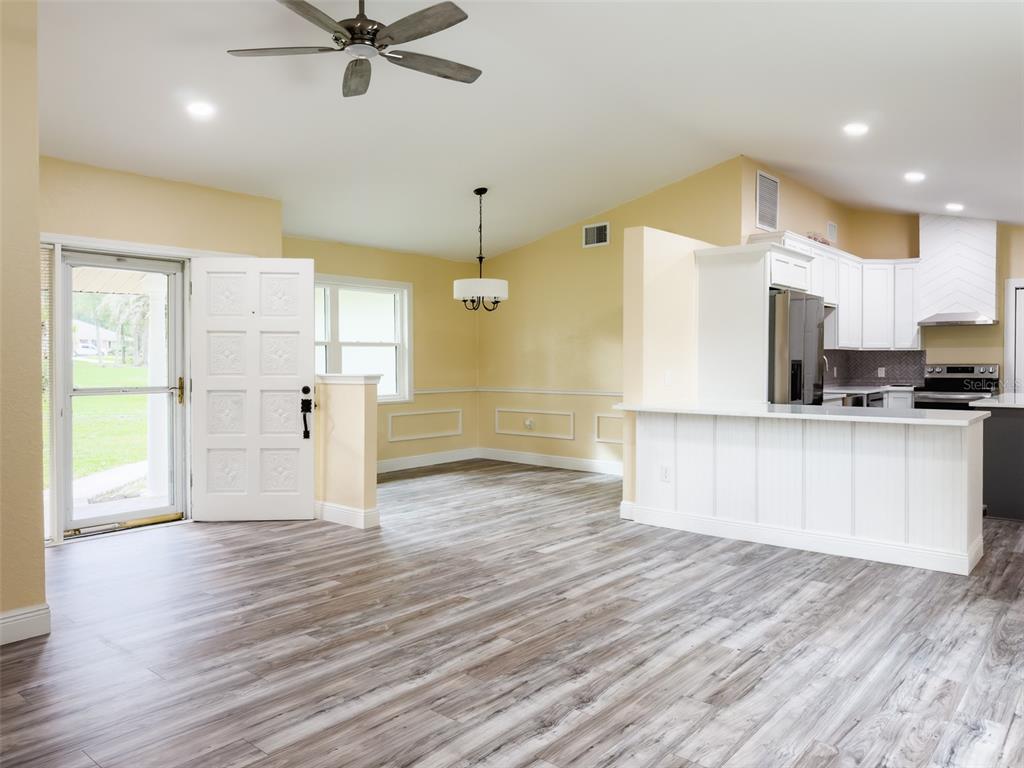 An open-concept room features light yellow walls, gray wood-look flooring, and a white kitchen island — 14522 SE 1ST AVENUE RD, SUMMERFIELD, FL