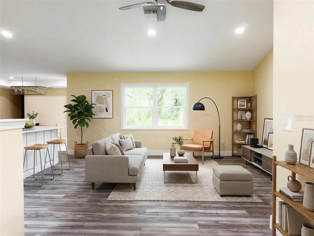 A living room with gray wood-look flooring, a light gray sofa, and a central window — 14522 SE 1ST AVENUE RD, SUMMERFIELD, FL