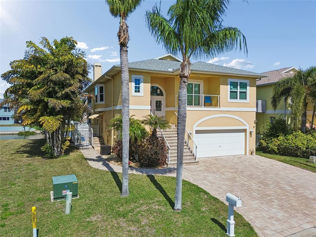 A two-story yellow house with a two-car garage, front stairs, and two tall palm trees — 6170 SEASIDE DRIVE, NEW PORT RICHEY, FL