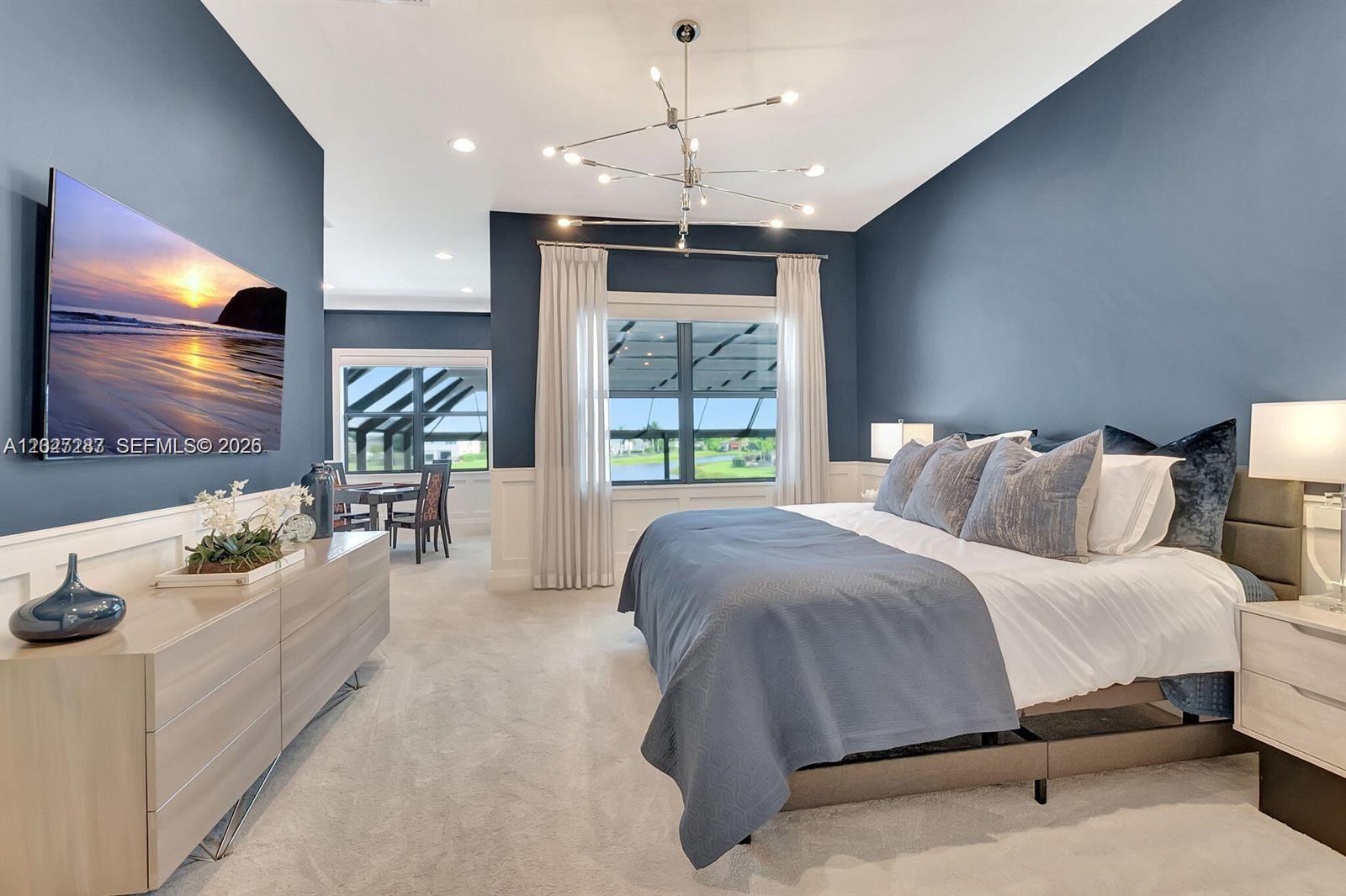 A bedroom features blue walls, a modern chandelier, a bed, and a view of water — 17230 Brulee Breeze Way, Boca Raton FL 33496, BOCA RATON, FL