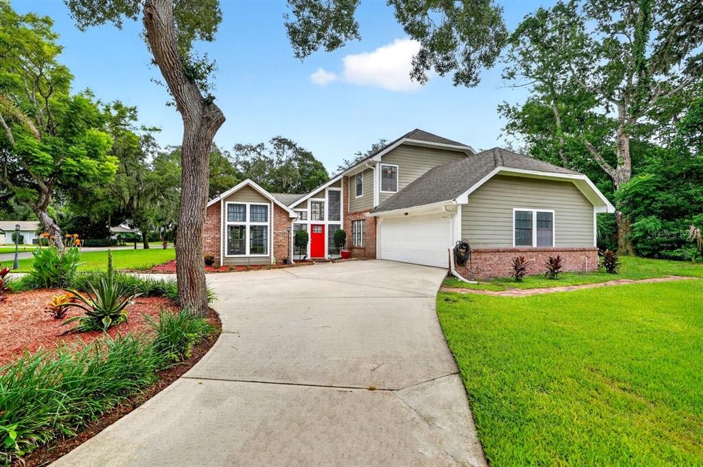 A two-story house with a brick and siding exterior, a red front door, and a driveway — 1 EAGLE ROCK TRAIL, ORMOND BEACH, FL
