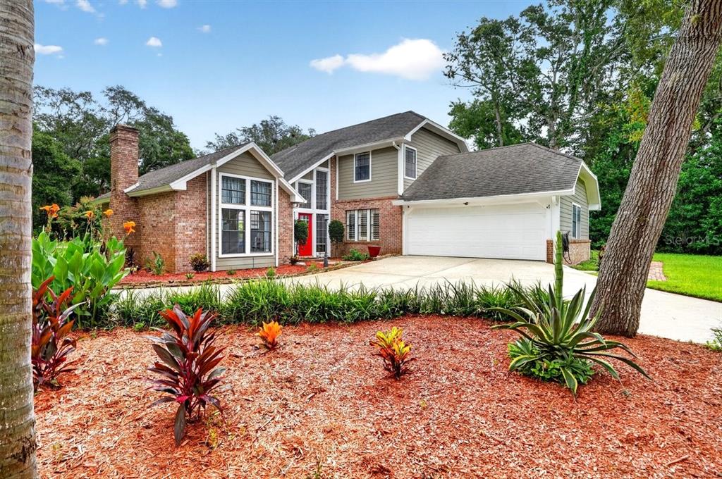 A two-story house with a brick and siding exterior, a red front door, and a garage — 1 EAGLE ROCK TRAIL, ORMOND BEACH, FL