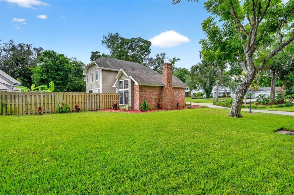 A two-story house with a brick chimney and a wooden fence stands on a lawn — 1 EAGLE ROCK TRAIL, ORMOND BEACH, FL