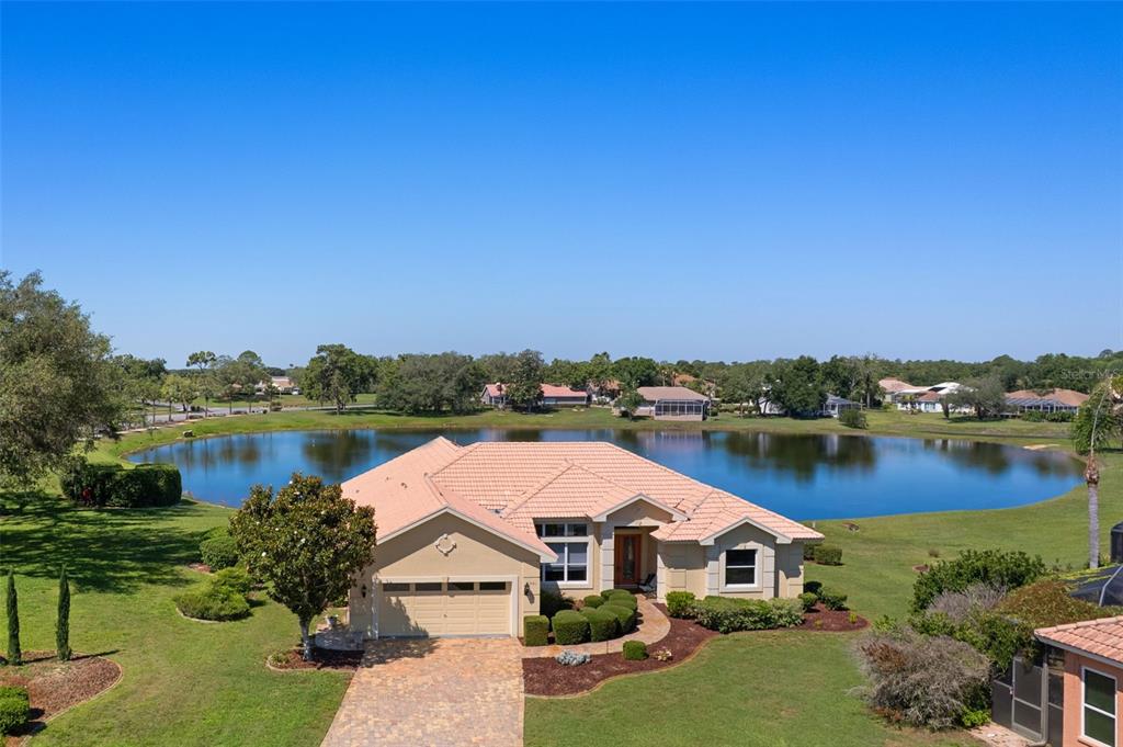An aerial view of a single-story house with a tile roof facing a lake — 10081 GEORGETOWN COURT, WEEKI WACHEE, FL