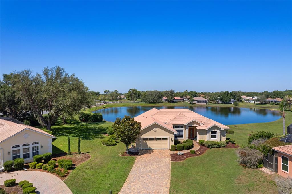 An aerial view shows a single-story house with a tile roof beside a lake — 10081 GEORGETOWN COURT, WEEKI WACHEE, FL