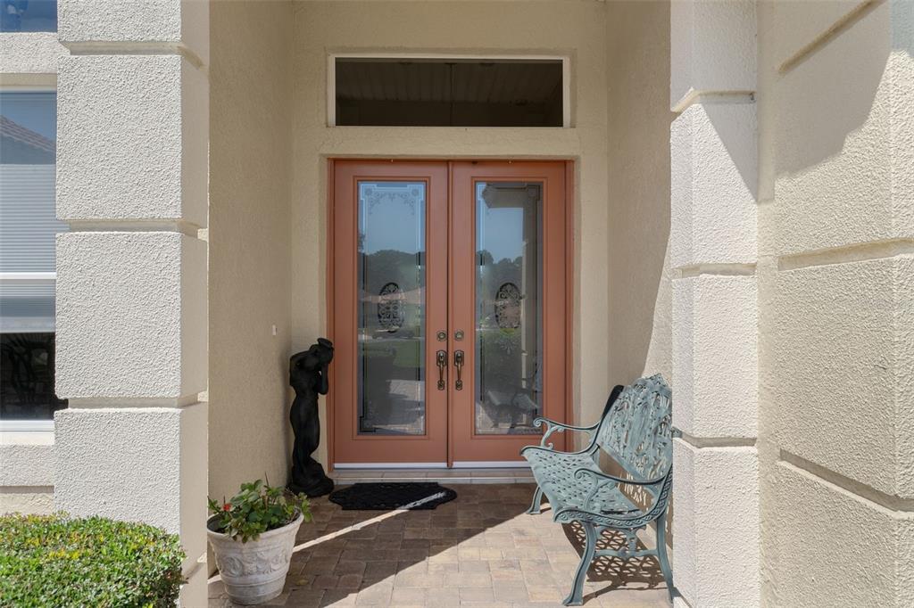 A front entryway features double glass-paneled doors, a metal bench, and a decorative statue — 10081 GEORGETOWN COURT, WEEKI WACHEE, FL