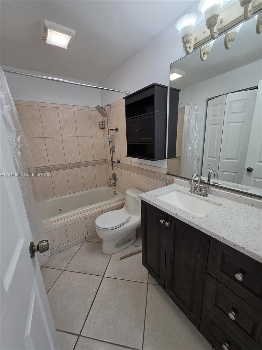 A bathroom features a tiled tub-shower combination, a dark wood vanity, and a toilet — 5720 Douglas St, Hollywood FL 33021, HOLLYWOOD, FL