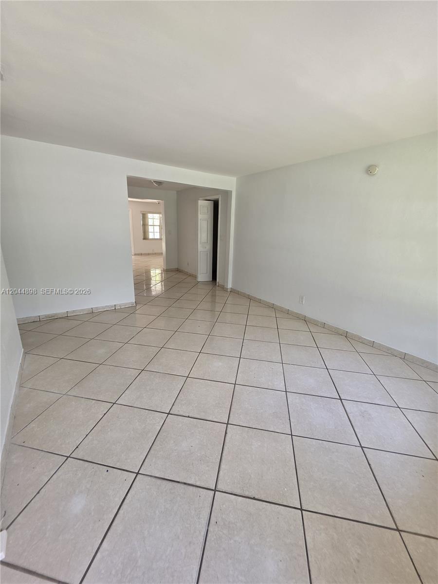 An empty room features white walls and light-colored square floor tiles laid on a diagonal — 5720 Douglas St, Hollywood FL 33021, HOLLYWOOD, FL