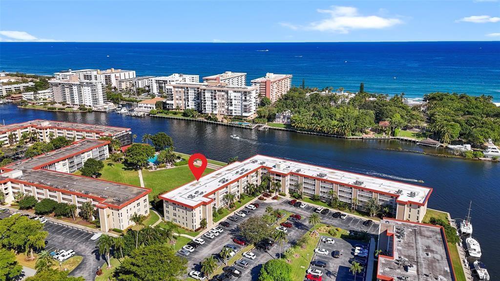 An aerial view shows a multi-story apartment complex situated along a waterway near the ocean — 3100 NE 48th Court # 413, Lighthouse Point FL 33064, LIGHTHOUSE POINT, FL