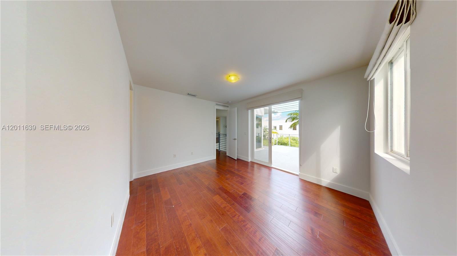 An empty bedroom features hardwood floors, white walls, and a sliding glass door to a balcony — 9980 NW 74th Ter, Doral FL 33178, DORAL, FL
