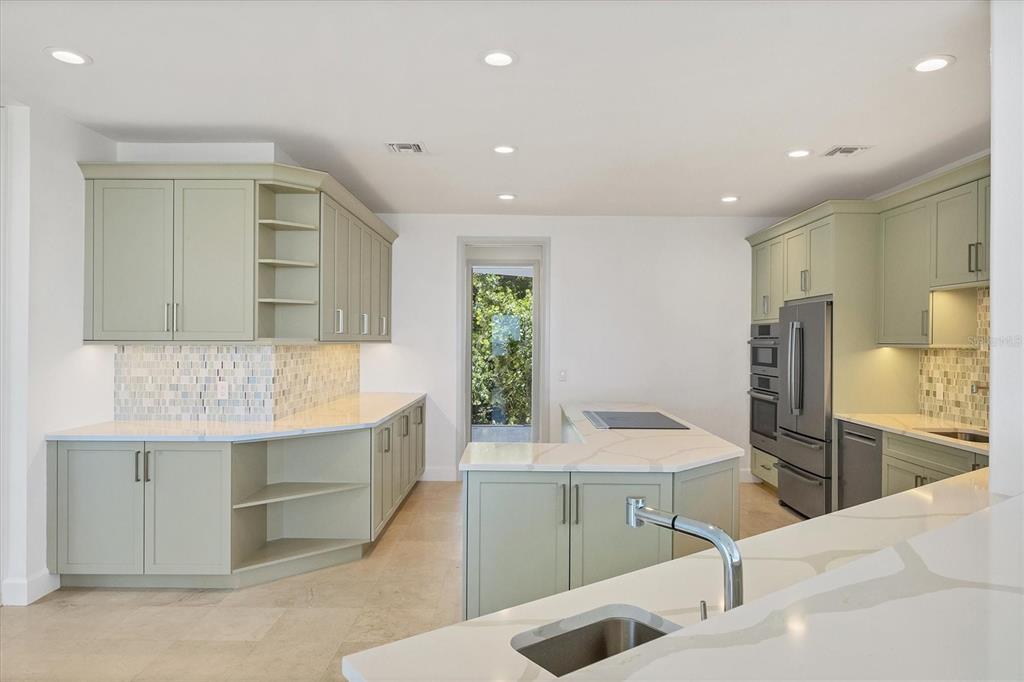 A kitchen features sage green cabinets, white countertops, a central island, and a mosaic backsplash — 5801 GULF OF MEXICO DRIVE, LONGBOAT KEY, FL