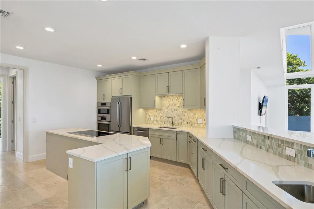 A kitchen features sage green cabinetry, white marble countertops, and a central island — 5801 GULF OF MEXICO DRIVE, LONGBOAT KEY, FL