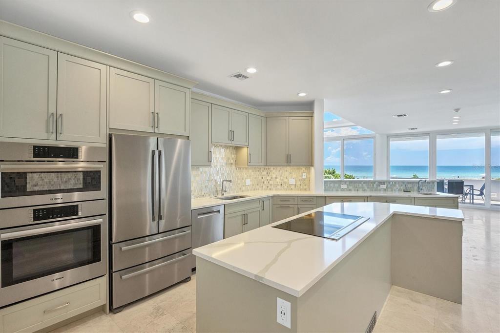 A modern kitchen features light-colored cabinetry, stainless steel appliances, a center island, and ocean views — 5801 GULF OF MEXICO DRIVE, LONGBOAT KEY, FL