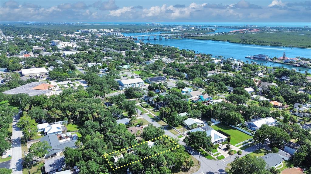 An aerial view shows a residential neighborhood with a highlighted property lot near the water — 1112 PALMETTO STREET, NEW SMYRNA BEACH, FL