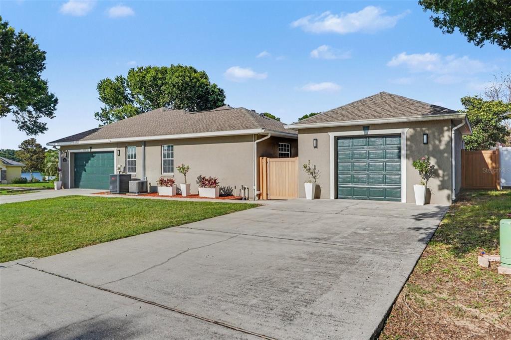 A single-story house with two green garage doors, a concrete driveway, and a wooden gate — 265 BAYBERRY DRIVE, POLK CITY, FL