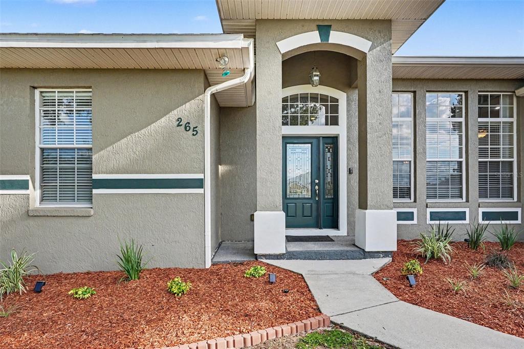 The exterior of a house features a dark green front door and a concrete walkway — 265 BAYBERRY DRIVE, POLK CITY, FL