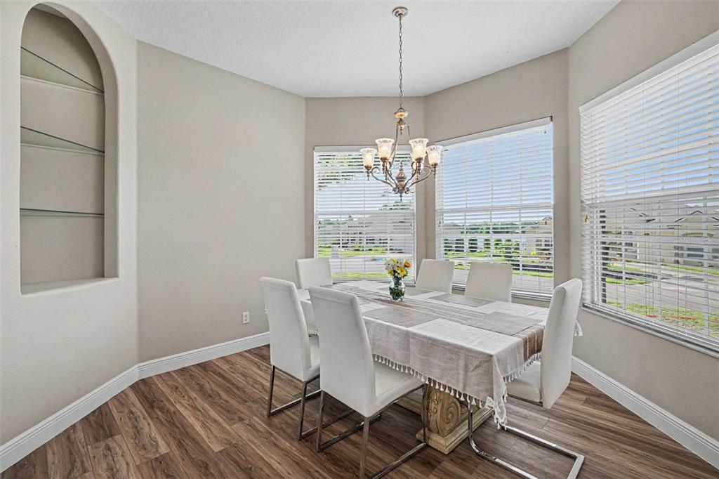 A dining room features a table with six white chairs, a chandelier, and arched shelving — 265 BAYBERRY DRIVE, POLK CITY, FL