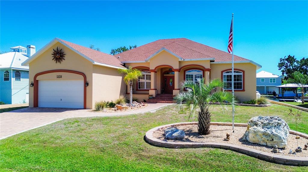 A single-story house with a tan exterior, a two-car garage, and a front yard — 1920 NW 16TH STREET, CRYSTAL RIVER, FL