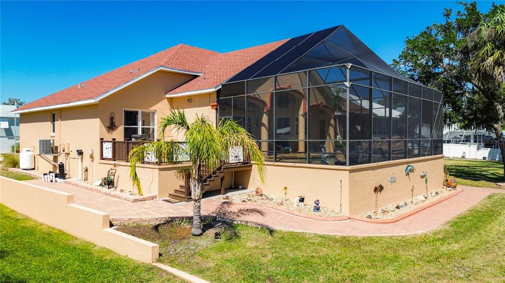 A tan house features a large screened-in pool enclosure and a paver walkway — 1920 NW 16TH STREET, CRYSTAL RIVER, FL