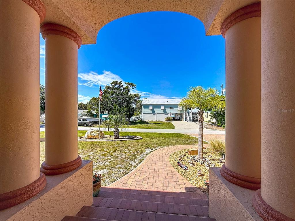 A view from a covered porch looking out toward a yard, driveway, and neighboring house — 1920 NW 16TH STREET, CRYSTAL RIVER, FL