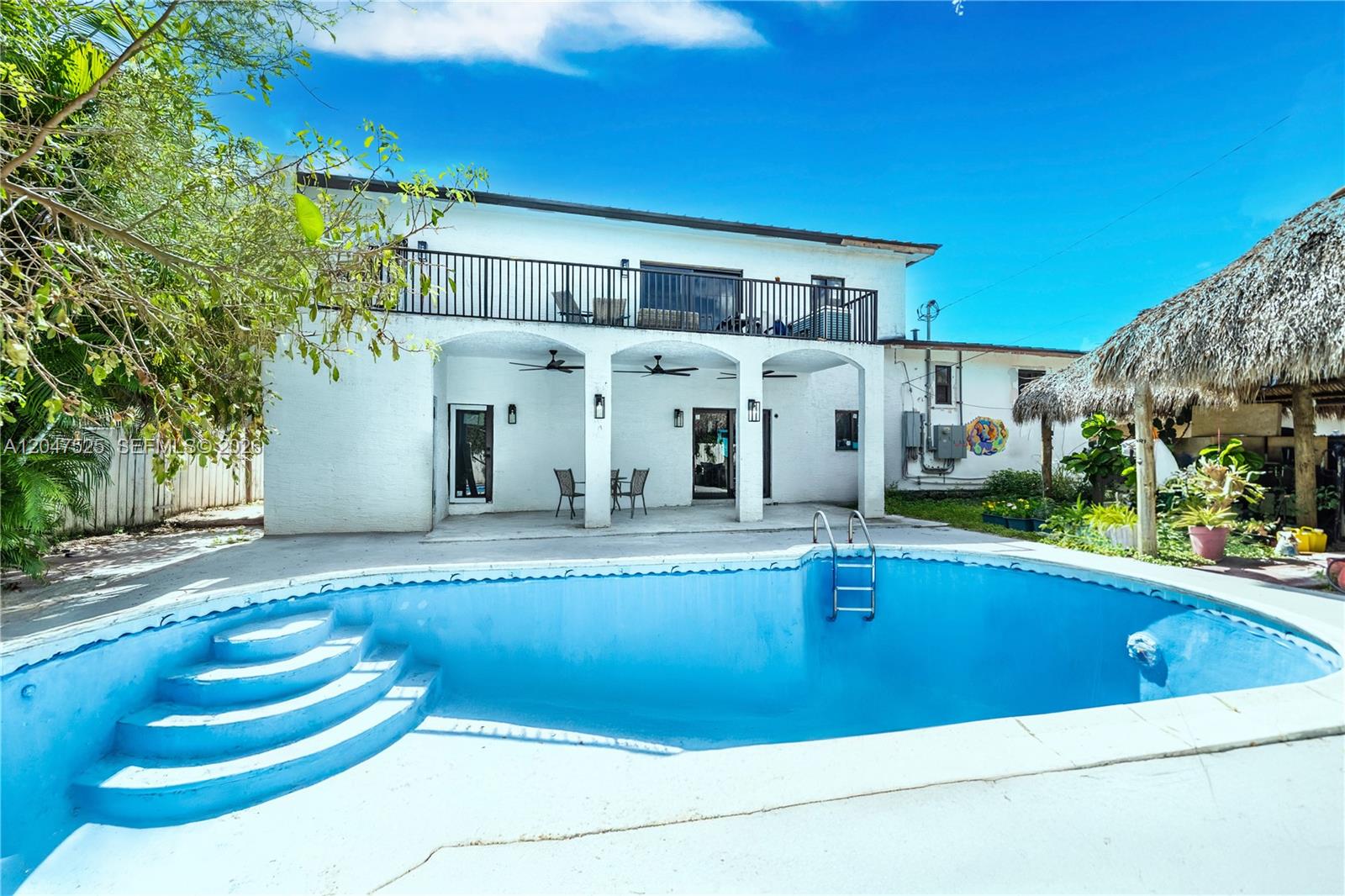 A two-story white house features a backyard swimming pool and a thatched-roof tiki hut — 20200 NE 14th Ave, Miami FL 33179, MIAMI, FL