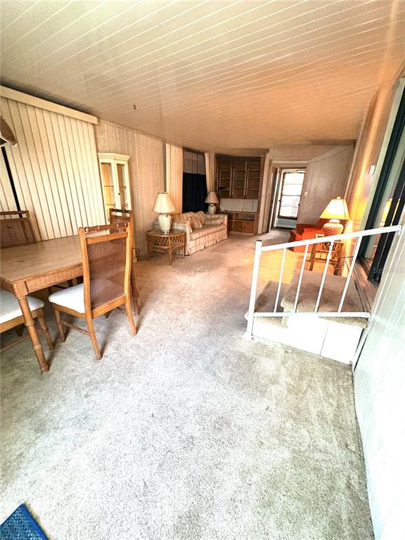 A carpeted sunroom features a dining set, a sofa, and a white metal railing — 22 WOODRUFF WAY, LAKE WALES, FL