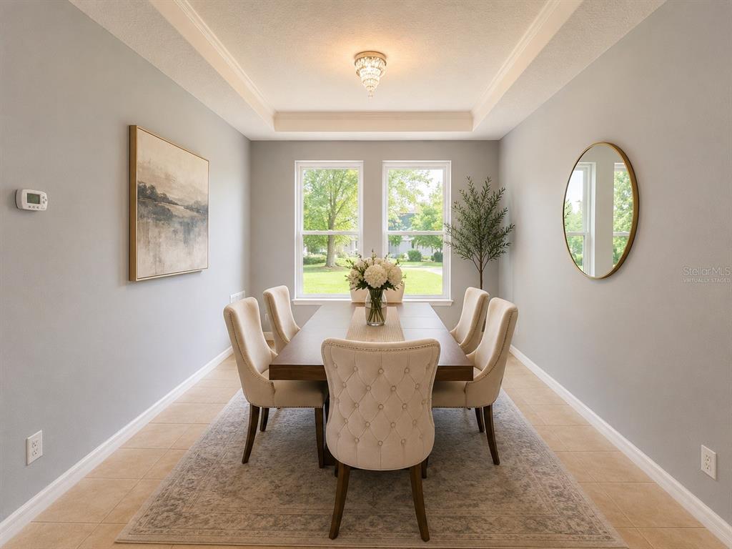 A dining room features a rectangular table with six tufted chairs under a tray ceiling — 5169 DOVE TREE STREET, ORLANDO, FL