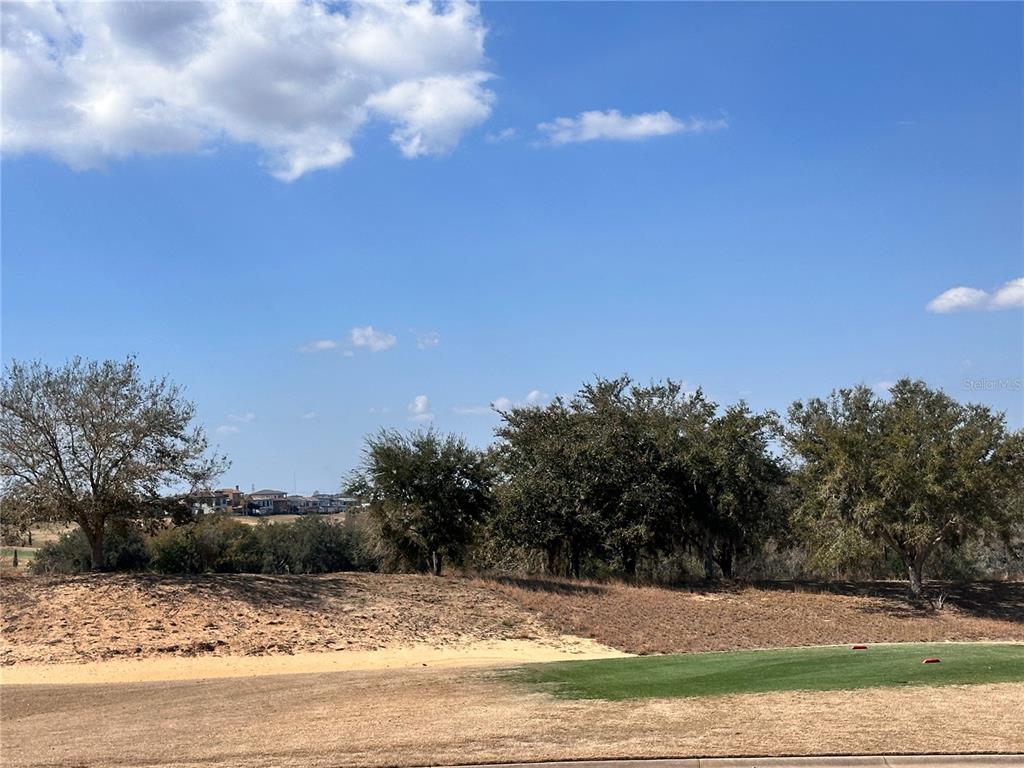 A view of a golf course fairway with trees and houses in the background — 16238 RAVENNA COURT, BELLA COLLINA, FL
