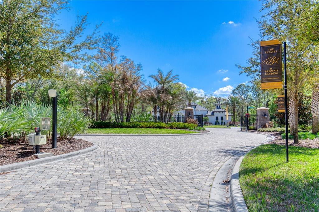 A paved driveway leads to the gated entrance of a residential community with lush landscaping — 1805 ADRIAN CREEK BOULEVARD, PORT ORANGE, FL