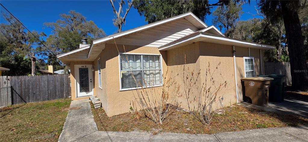 A tan, single-story house with a concrete walkway and a wooden fence in the yard — 721 NE 26TH STREET, OCALA, FL