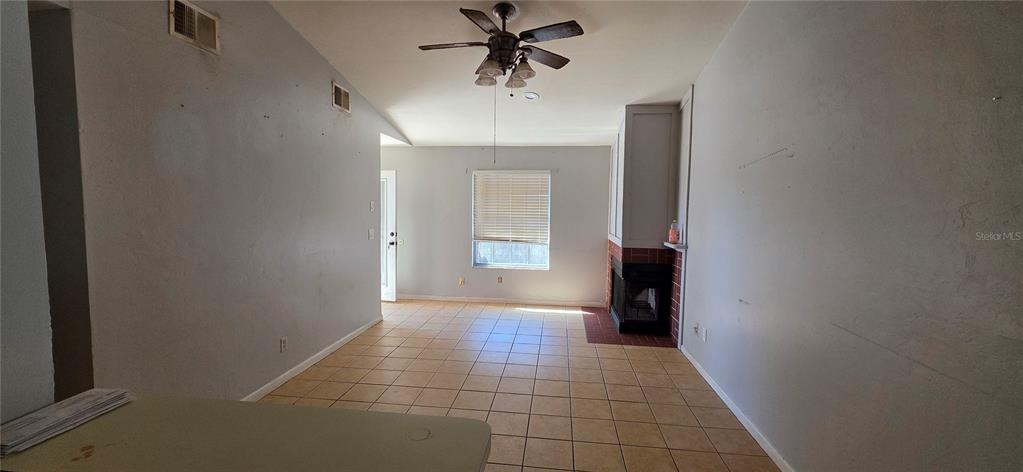 A living room features tile flooring, a vaulted ceiling with a fan, and a fireplace — 721 NE 26TH STREET, OCALA, FL