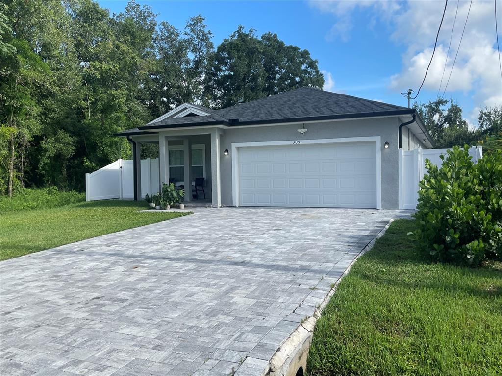 A single-story house with a gray stucco exterior, a paved driveway, and a white fence — 305 CYPRESS STREET, ORLANDO, FL